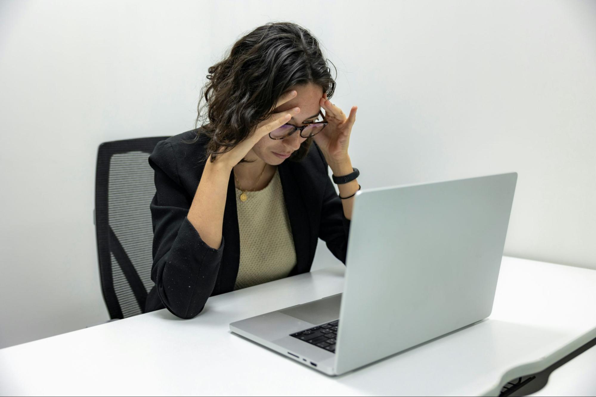 woman in front of a computer holding her head